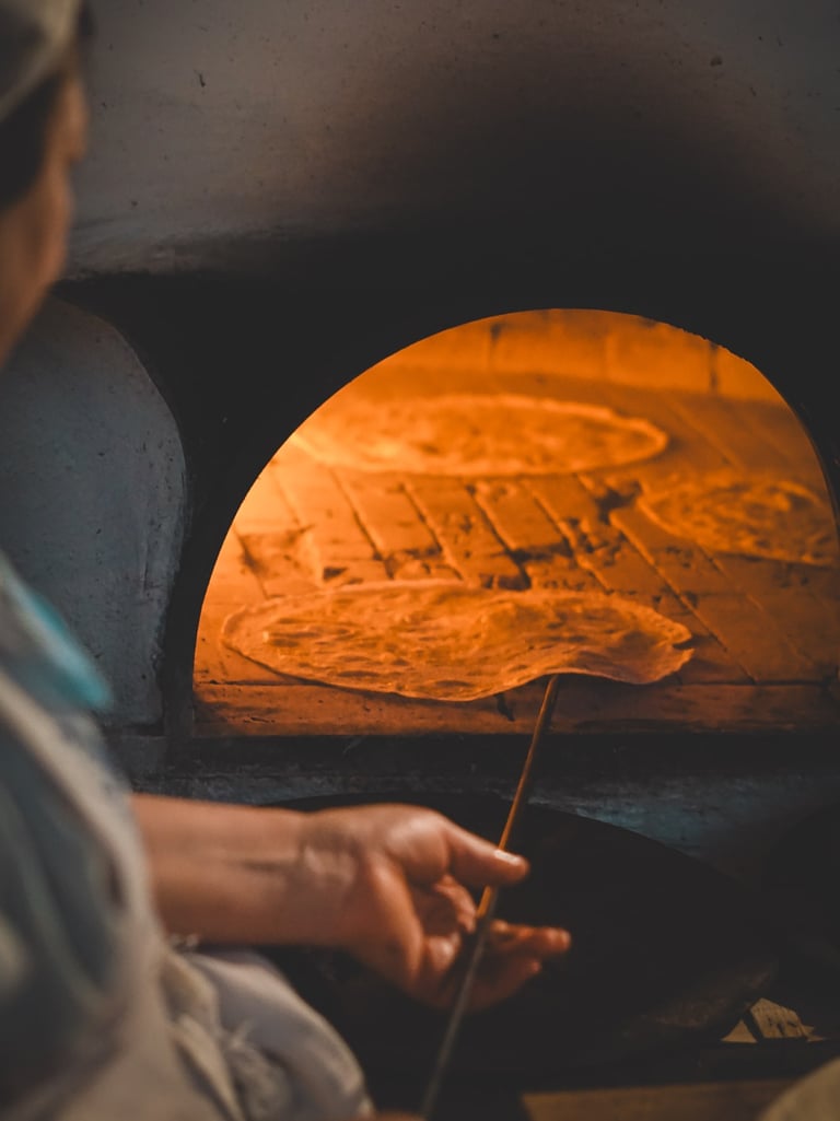 Traditional bread baking in Sardinia: a local woman cooks Pane Carasau in a wood-fired oven