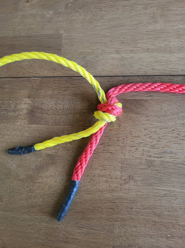 Flat overhand knot bend joining yellow poly line and red rope