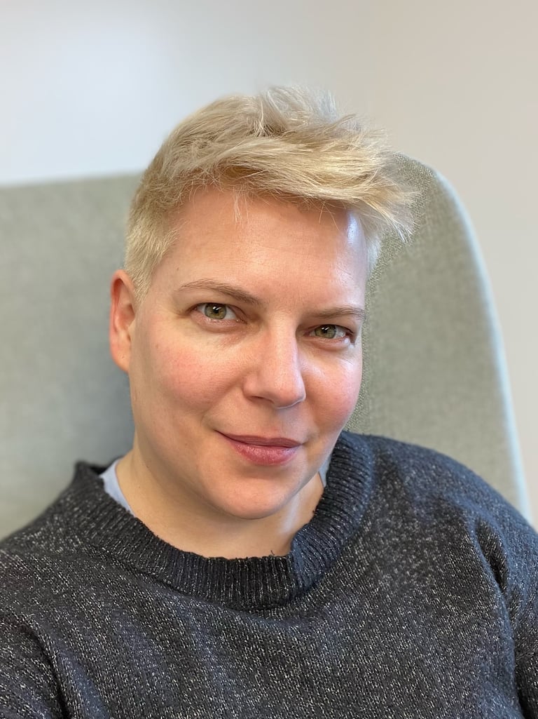 A woman with short bleached hair and a blue-gray sweater