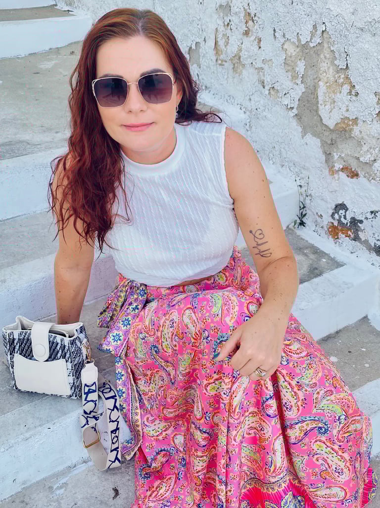 a woman in a white tank top and pink skirt
