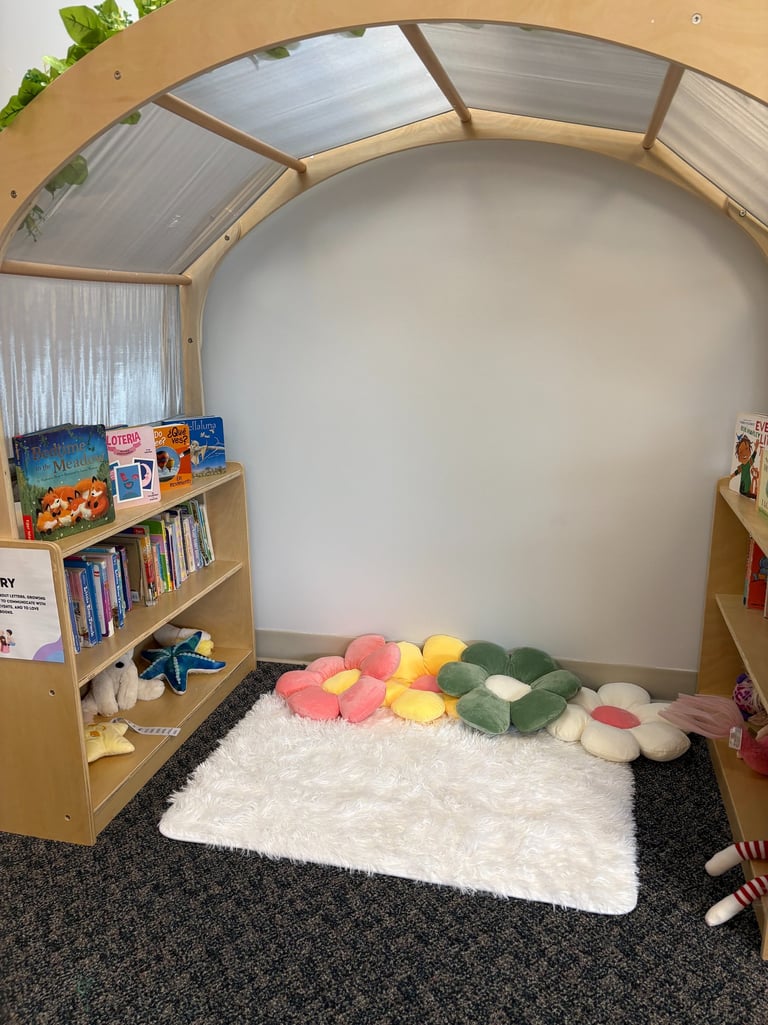 Cozy classroom reading nook with a wooden arch, bookshelves, flower floor pillows, and a white shag rug.