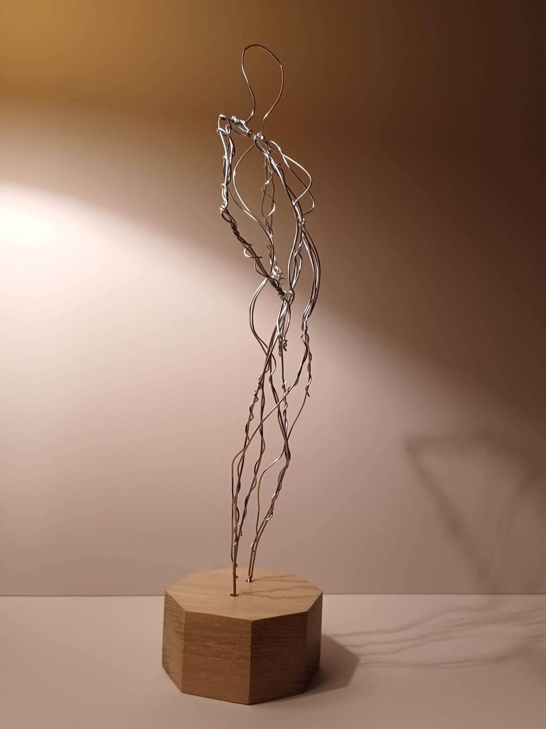 A wire sculpture of a complete female figure, standing with hands on hips