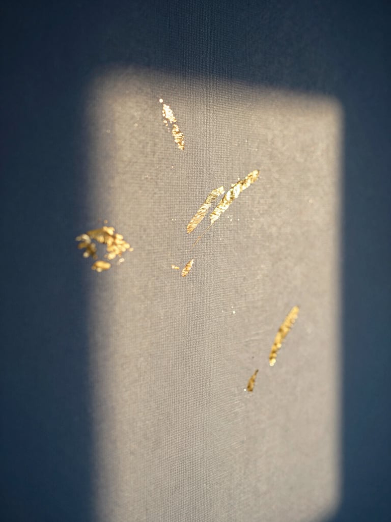 Vertical close-up of a textured canvas with gold leaf accents and dark blue pigments, twilight shadows