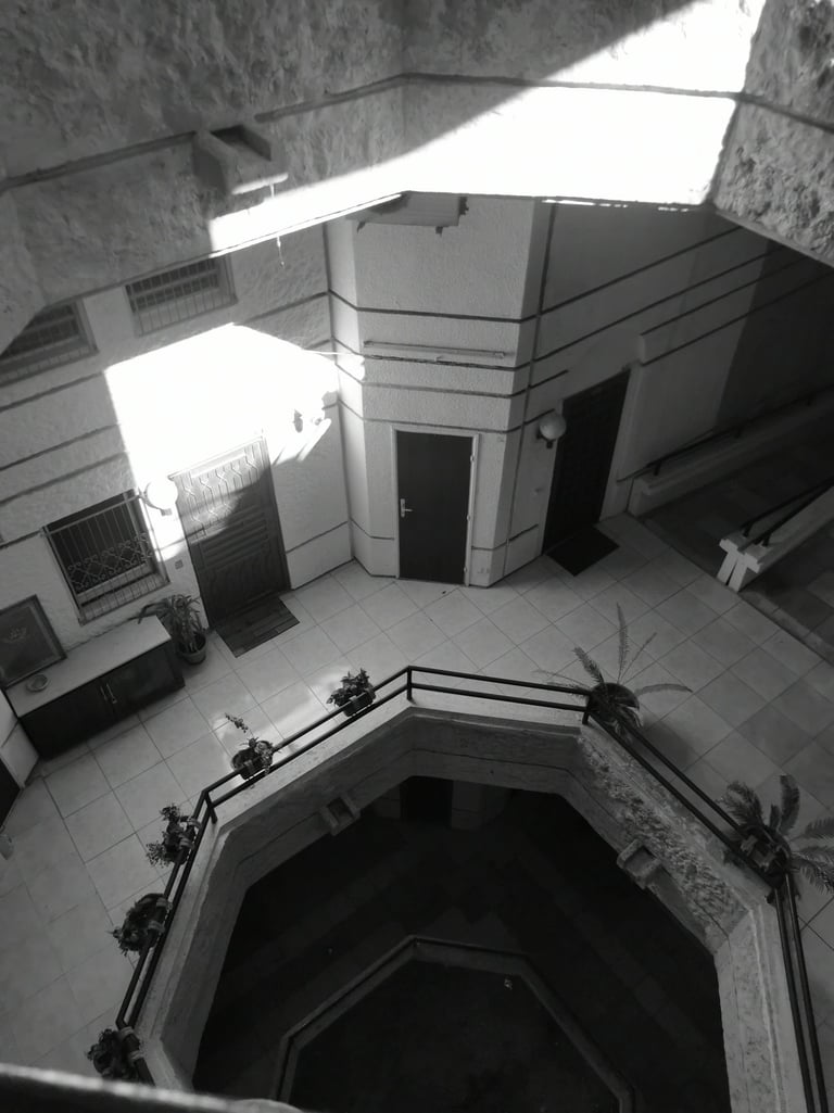 Black and white high-angle shot of brutalist building courtyard with tiled floors. Unseen Spaces