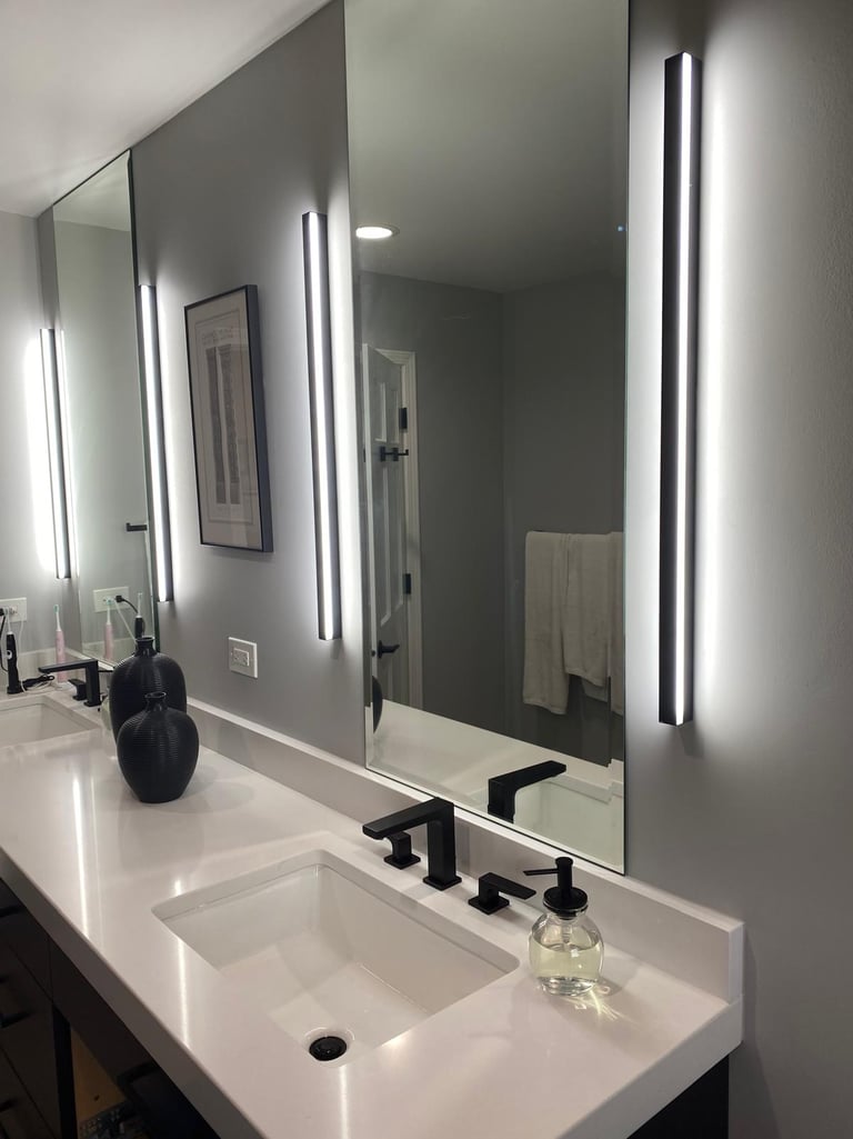 Modern bathroom vanity with white quartz countertop, black faucets, and vertical LED wall sconces beside mirrors.