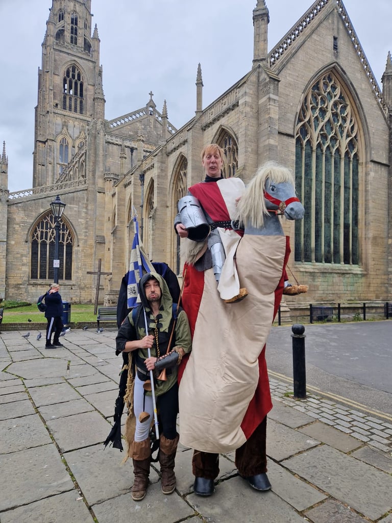 Medieval knight on a hobby horse with his squire standing in front of a historic gothic cathedral.