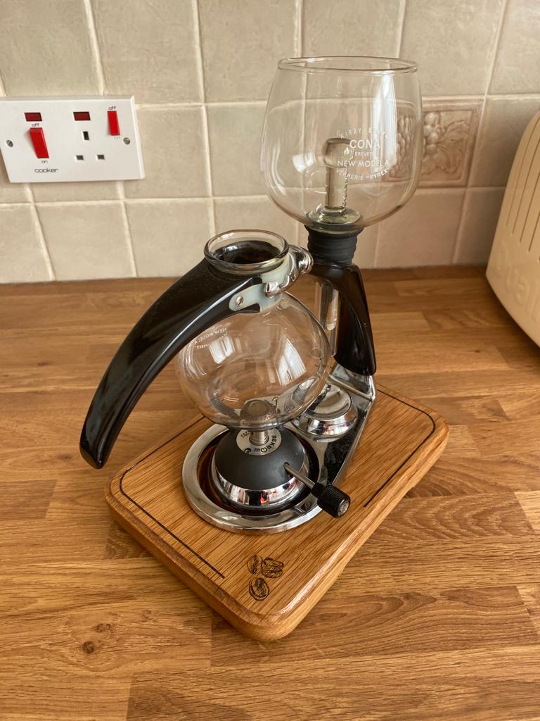 a coffee maker with a glass carafeine on a wooden stand