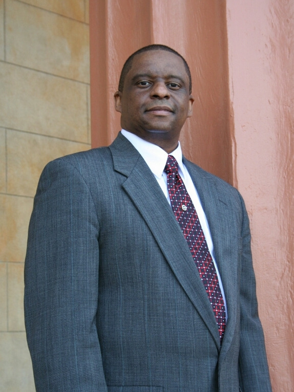 Mark T. Stewart in a suit and tie standing in front of the Old Courthouse