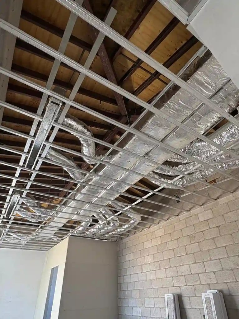 Ductería HVAC residencial con aislamiento plateado instalada en entretecho