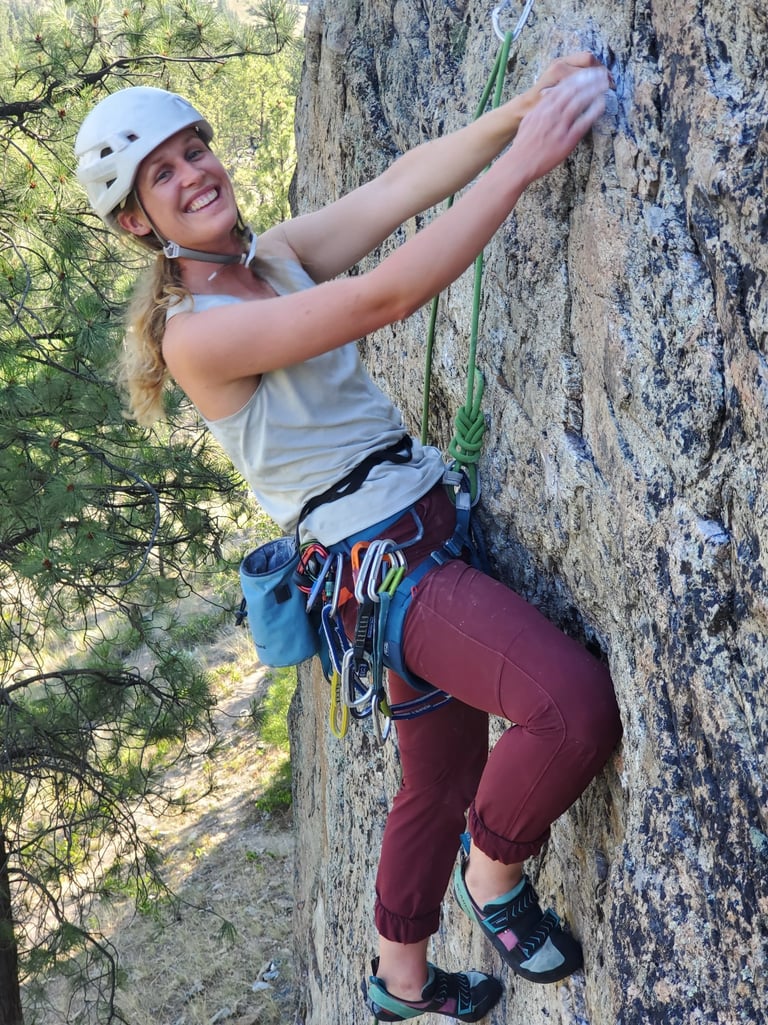 A smiling woman climbing an outdoor rock face
