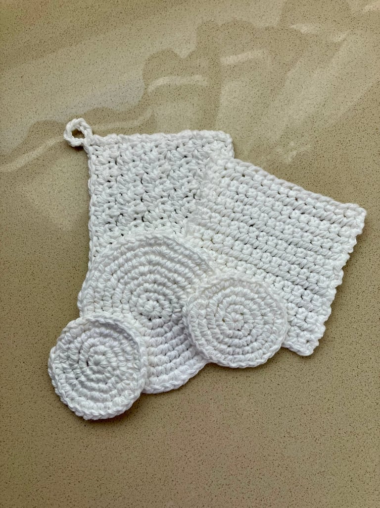 5 white crocheted face scrubbies lying on each other in round and square shapes