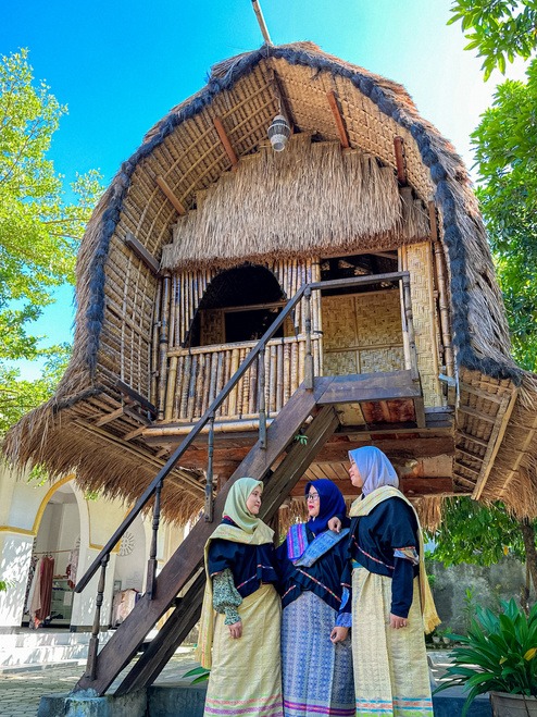 a group of women in traditional dress clothes standing in front of a thatched house in sade village