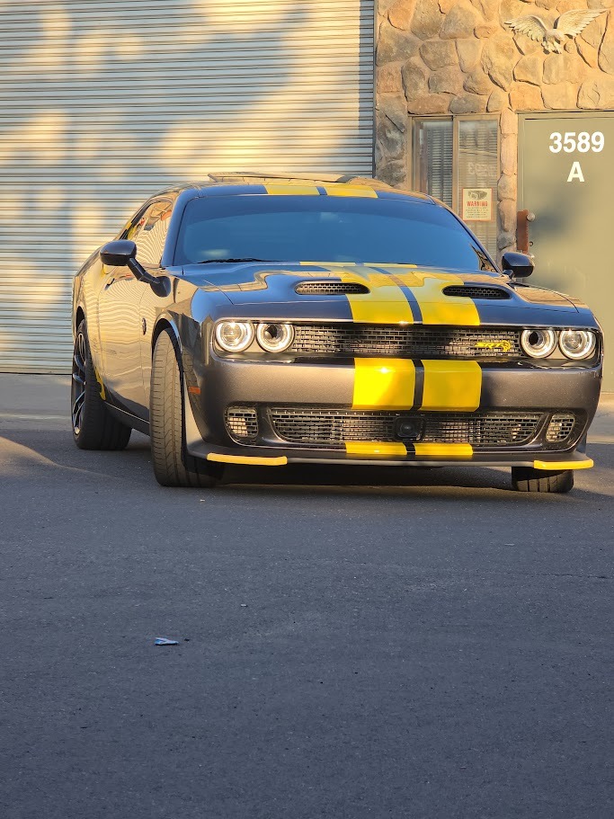 Custom automotive vinyl job: Yellow racing stripes applied from front to back on a black Dodge Chall
