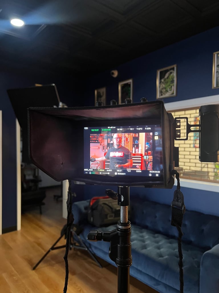 Professional film camera monitor displaying a man on set in a blue video production studio.