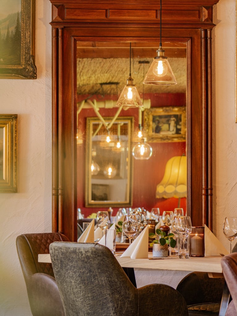 Elegant restaurant dining table with wine, glasses, and floral decor in a cozy, rustic setting with natural light and