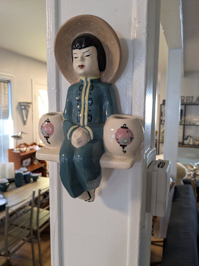 a ceramic figurine of a woman sitting on a shelf