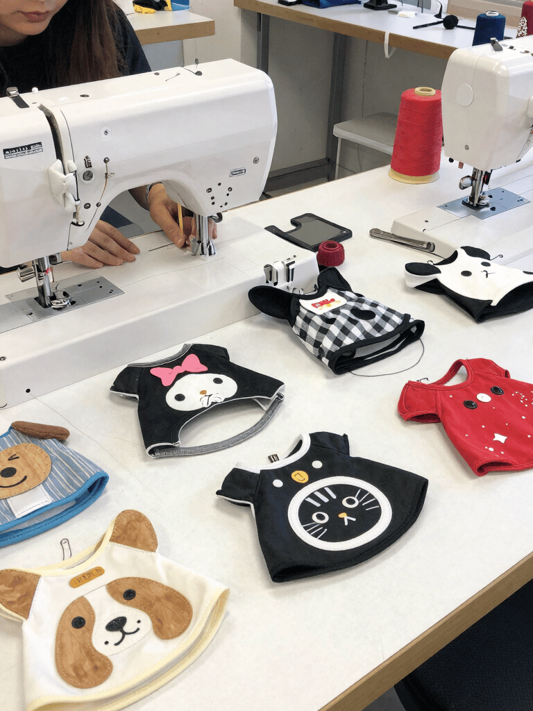 Una persona que utiliza una máquina de coser industrial para fabricar ropa y baberos para mascotas