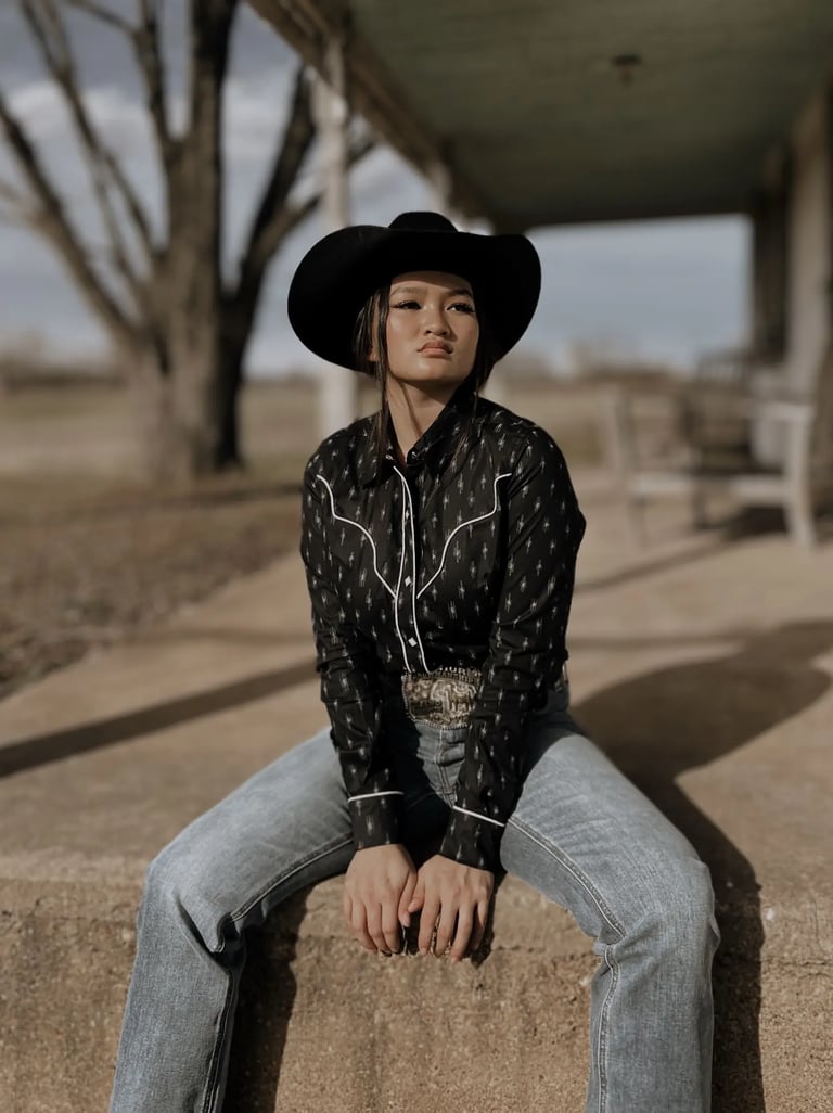 Woman sitting on a porch in a western shirt and jeans