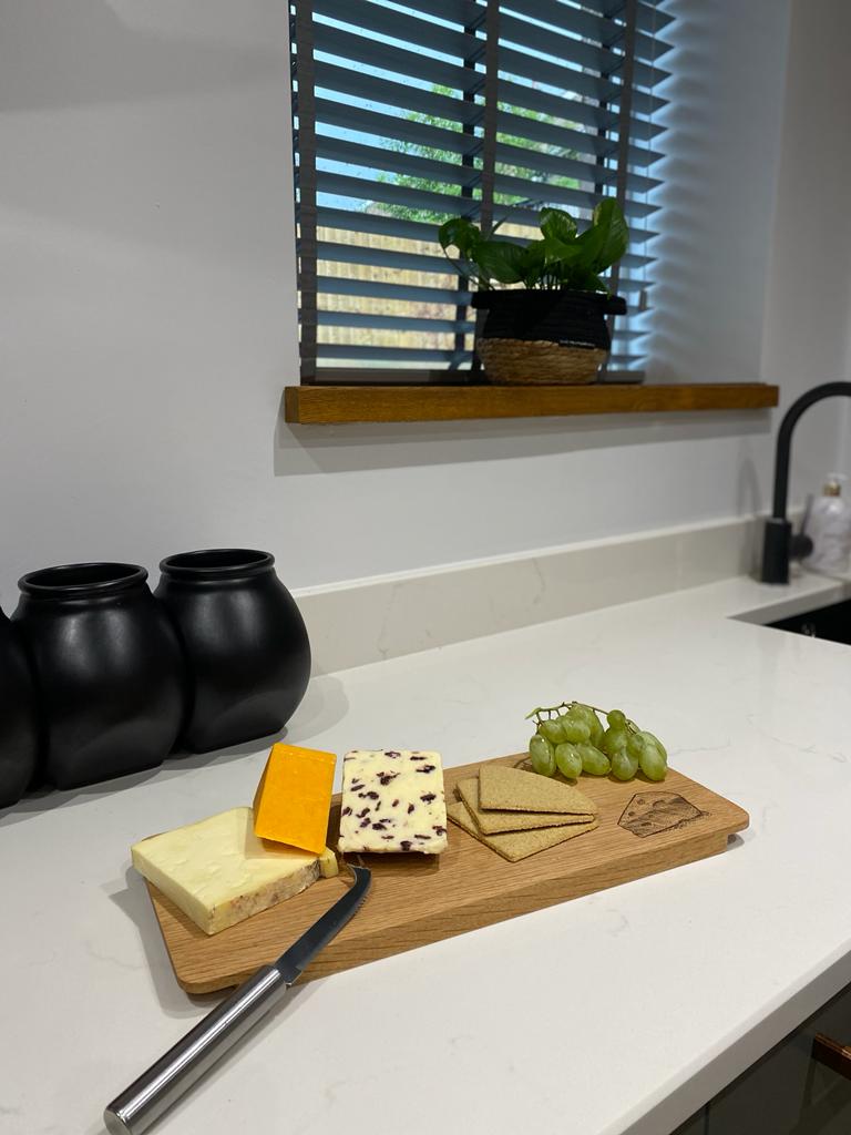 a cheese board with cheese and grapes on a kitchen bench