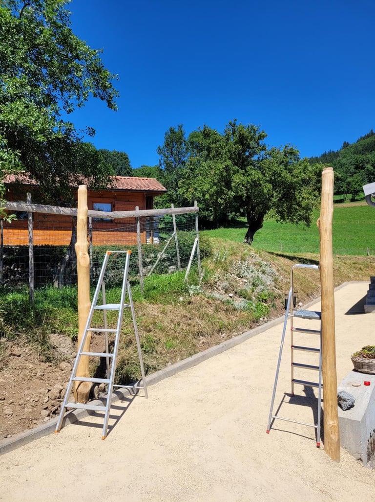 Two wooden gate posts installed near metal ladders on a new garden gravel path.