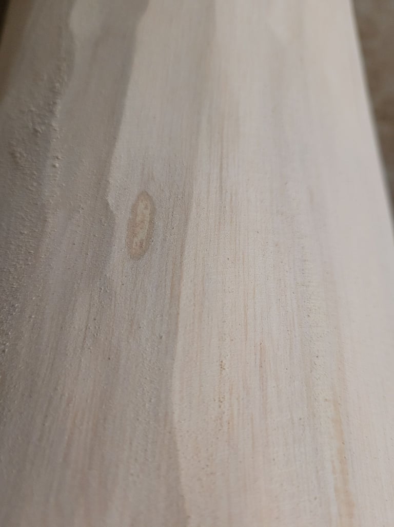 Close-up of smooth light-colored wood grain texture on a natural lumber plank.