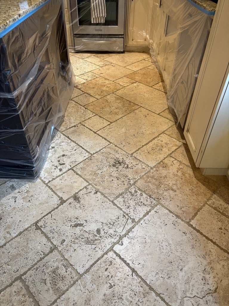 Dirty travertine tile floor in kitchen before professional cleaning
