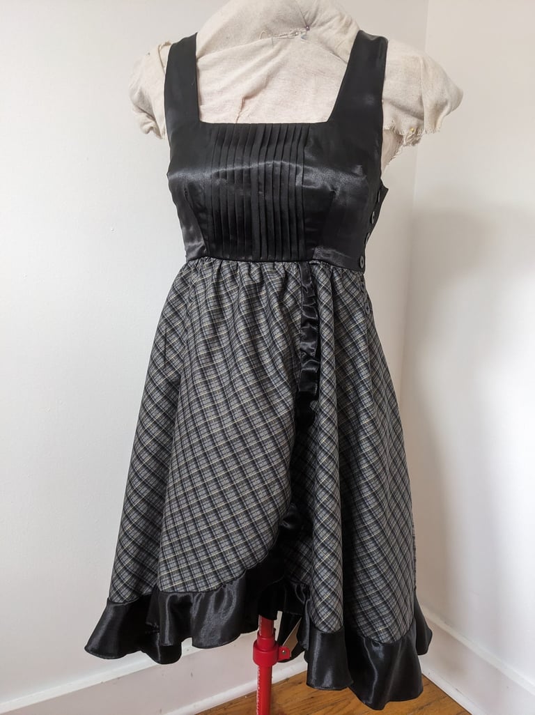 The front of a black/gold plaid and black satin flowy cocktail dress
