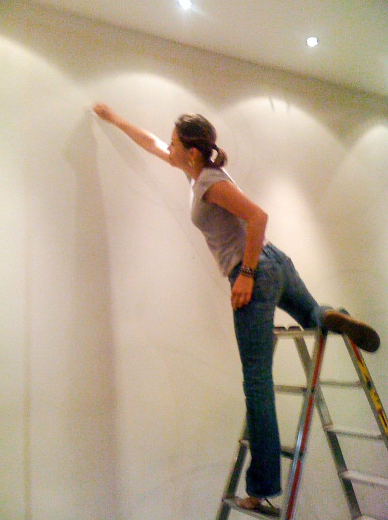 Stefanie on ladder sketching a mural.