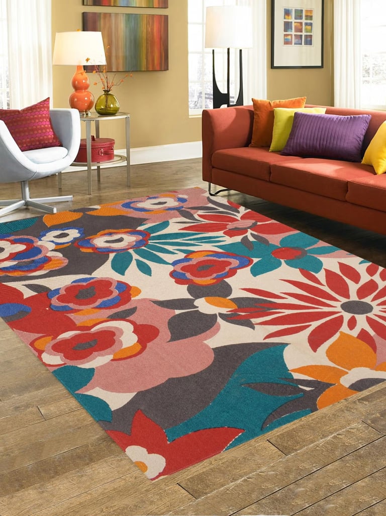 Modern living room with a vibrant floral area rug, orange sofa, and colorful accent pillows.