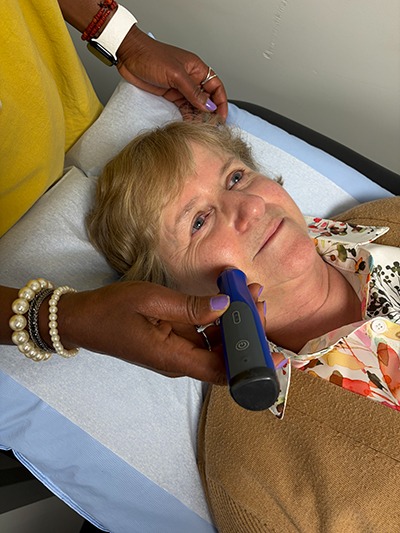 older woman laying on a doctors table receiving microneedling treatment