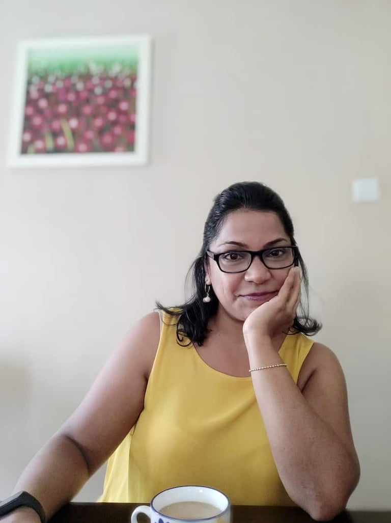 girl in yellow top, glasses, hand on chin with a slow easy smile
