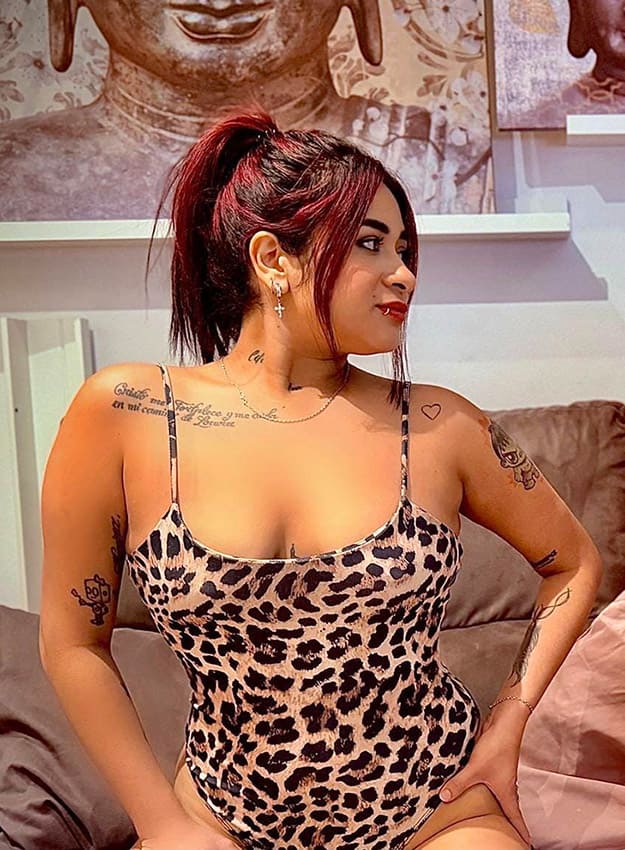 Chica colombiana en body animal print sobre el sofá mostrando su escote