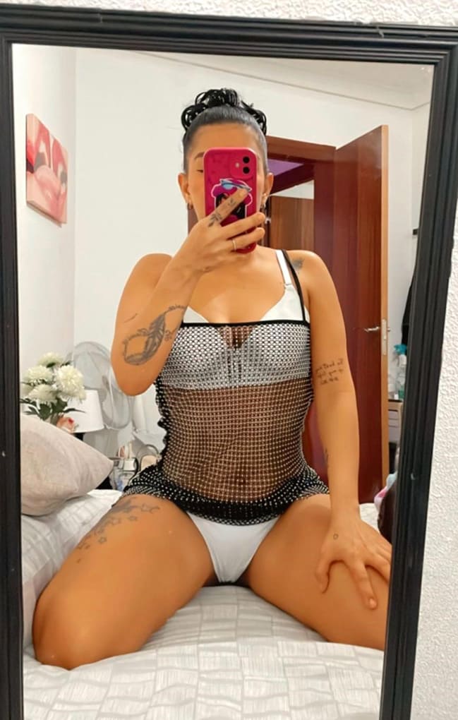 chica escort en Sabadell haciendo un selfi en una cama en ropa interior blanca y con las piernas abiertas