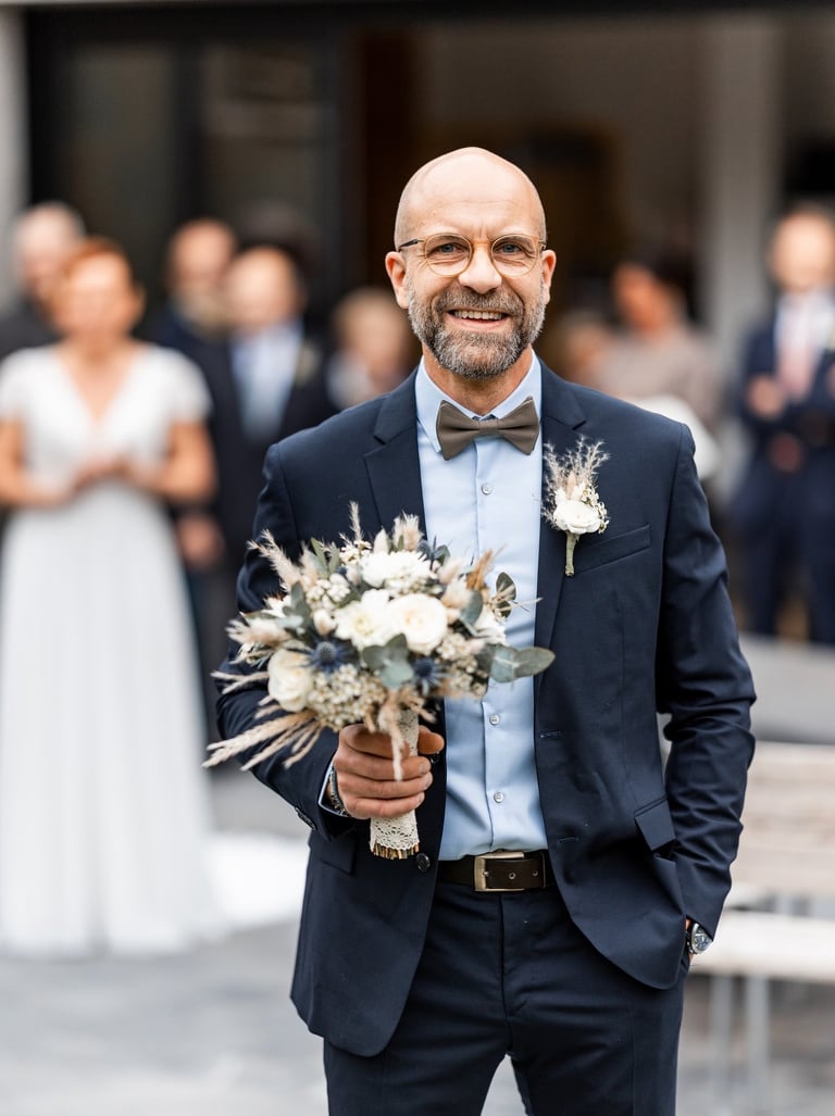 Un homme en costume avec un bouquet de fleurs à la main