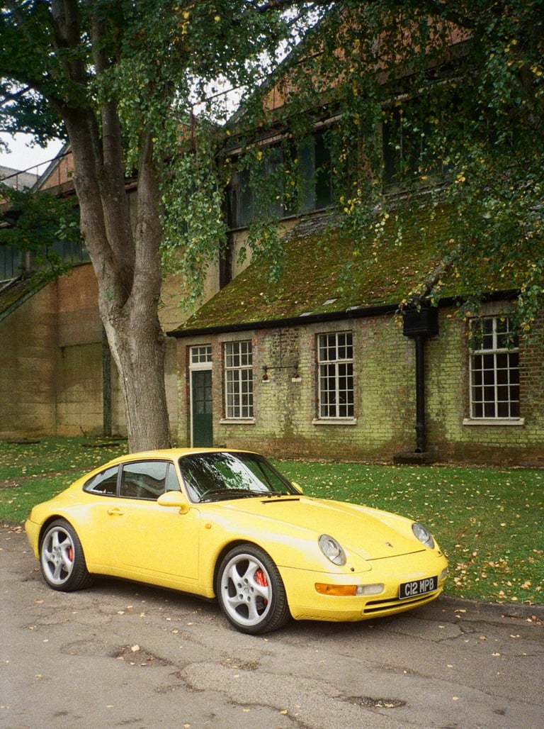 a yellow Porsche parked in front of a brick building