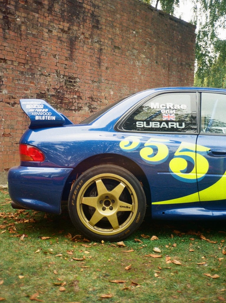 a Subaru Impreza rally car parked in front of a brick building