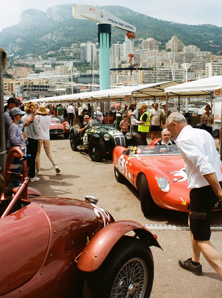 a man in a white shirt and black shorts is walking across of a group of race cars in the paddoc