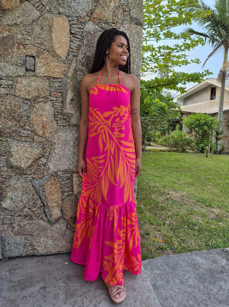 Mulher em pé usando um vestido com babado franzido, estampado nas cores rosa e laranja