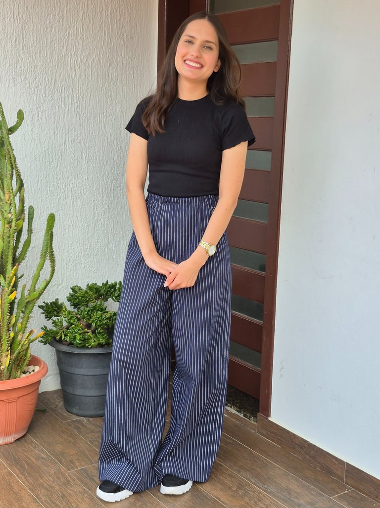 Mulher em pé uma calça azul marinho com estampa risca de giz