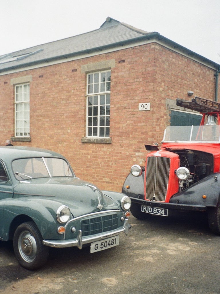 two classic cars parked in front of a brick building