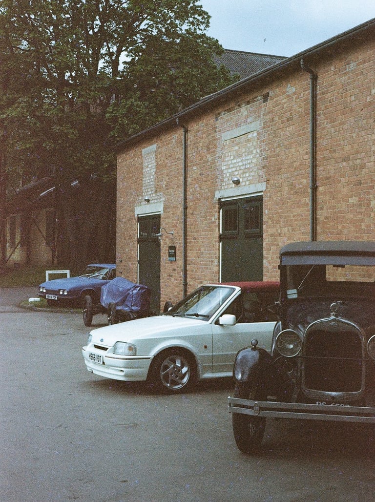a selection of classic cars parked in front of a brick building