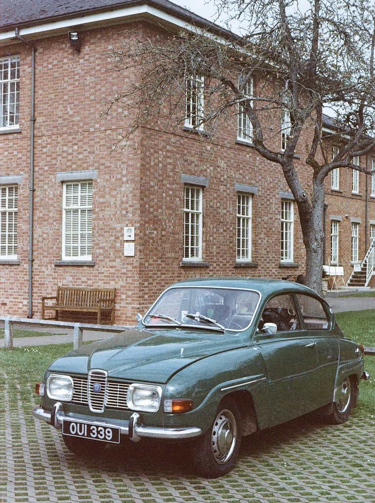 a green classic car parked in front of a brick building