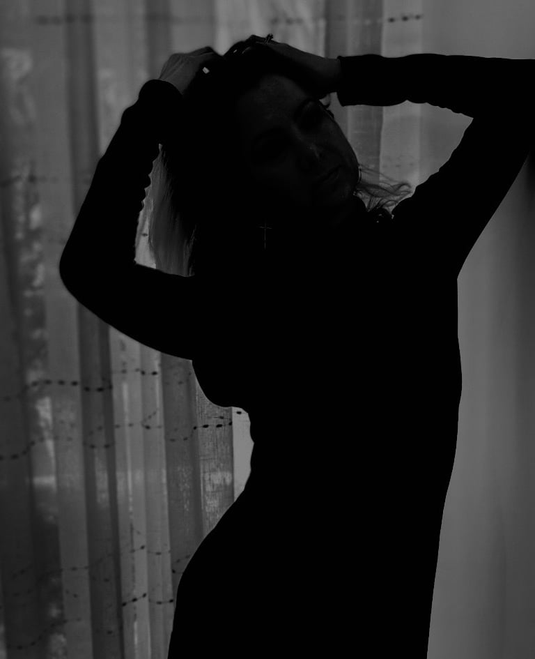 silhouette of author, artist, and shadow work coach LVF.LVX woman standing in front of a window 