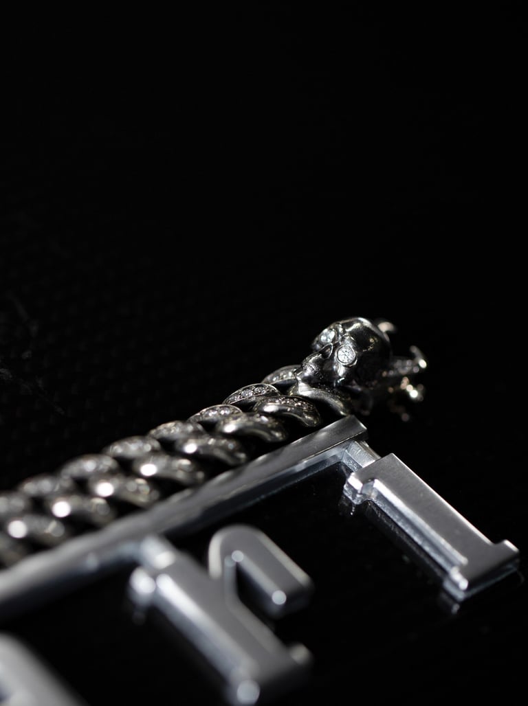 Macro product photo of a silver bracelet and metal pendant on a black background