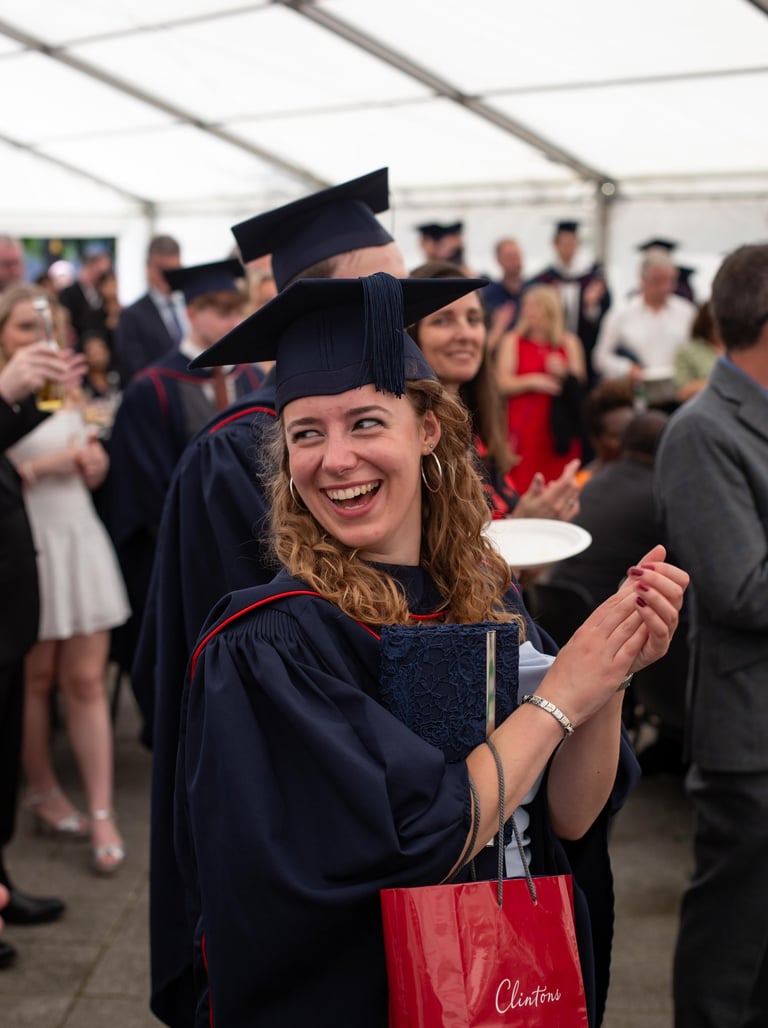 Graduation event photo of a smiling graduate in cap and gown
