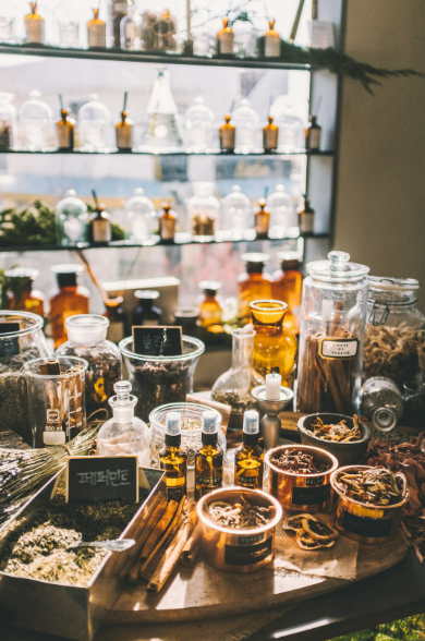 Artisanal perfume blending station with glass apothecary bottles and raw ingredients for bespoke fragrance creation.