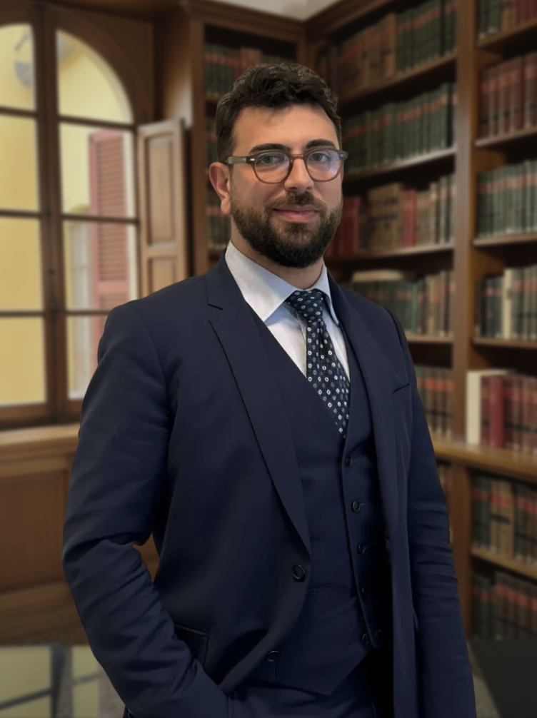 Lawyer in a navy blue three-piece suit standing in a classic library with bookshelves.