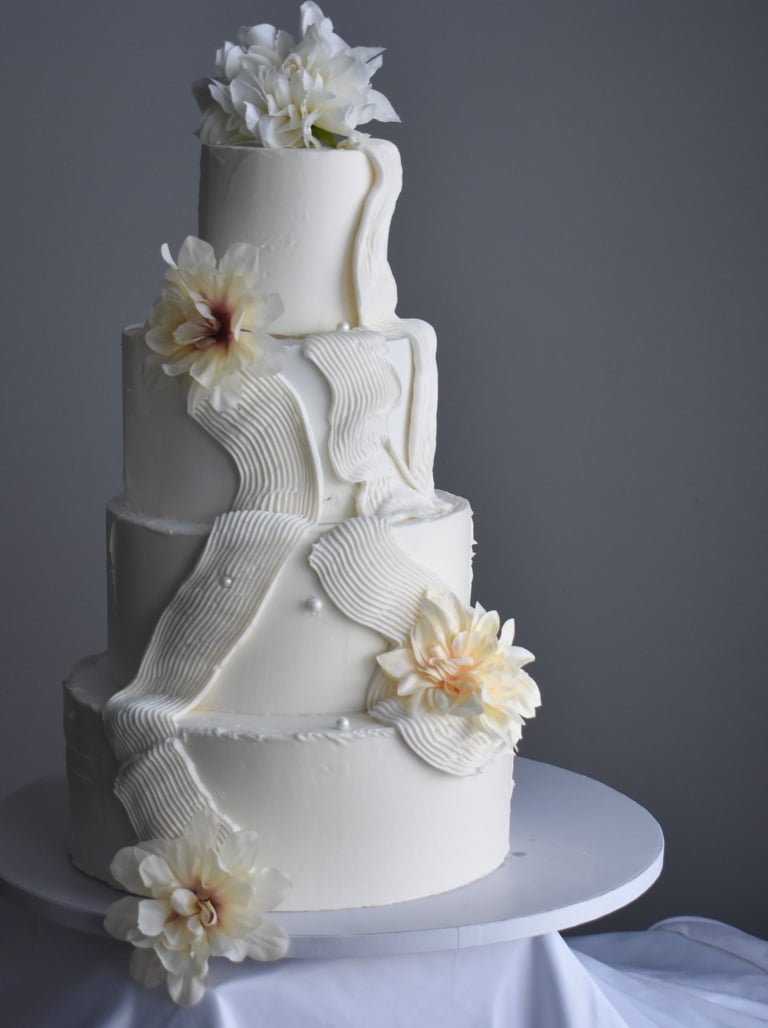 Elegant four-tier white wedding cake with textured buttercream ribbons & delicate silk in Chicago. 