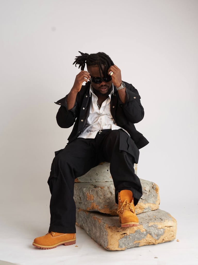 a man in a suit and sunglasses sitting on a rock