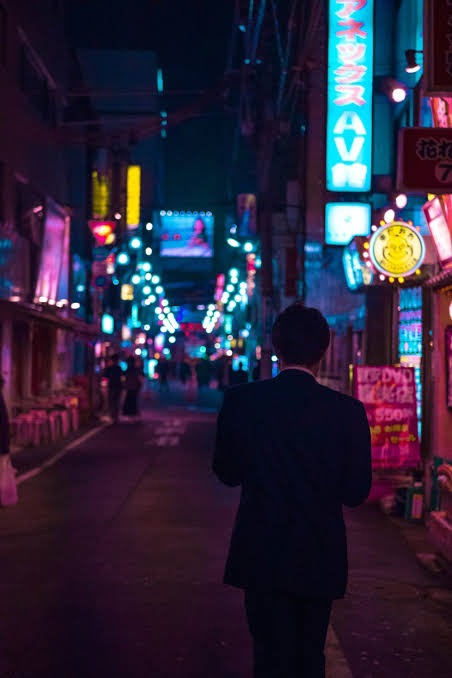 a man in a suit walking down a neon light street